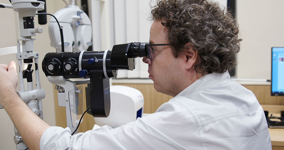 Augenarzt Dr. Horst Fischer schaut durch ein Mikroskop